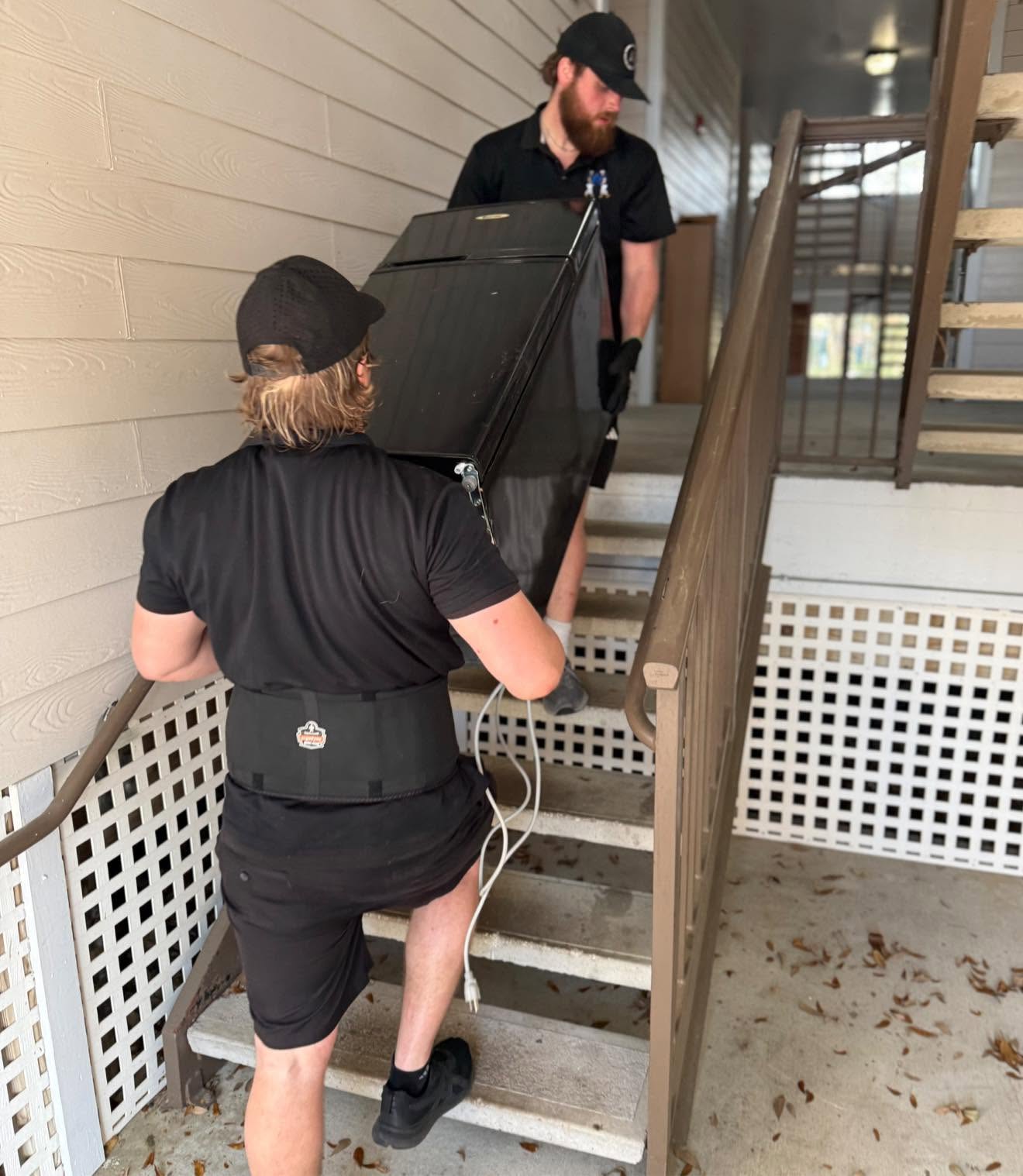 Arnold Brothers moving crew carrying an appliance up exterior stairs