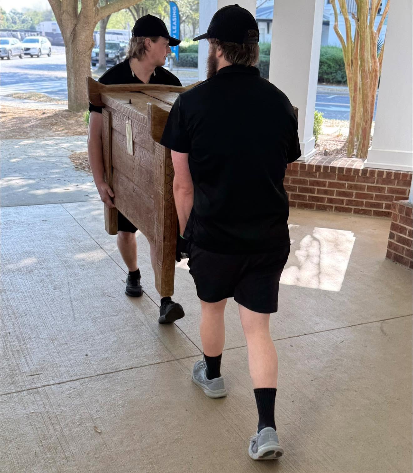 Two Arnold Brothers movers carrying a wooden chest