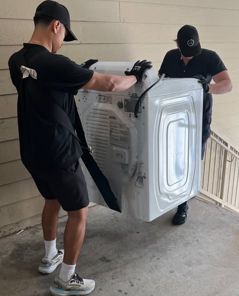 Two Arnold Brothers movers carefully carrying a washing machine
